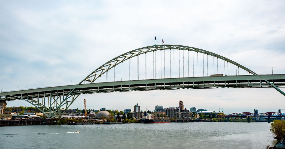 The iconic Fremont Bridge spans the Willamette River in Portland, Oregon, with the city skyline in the background.